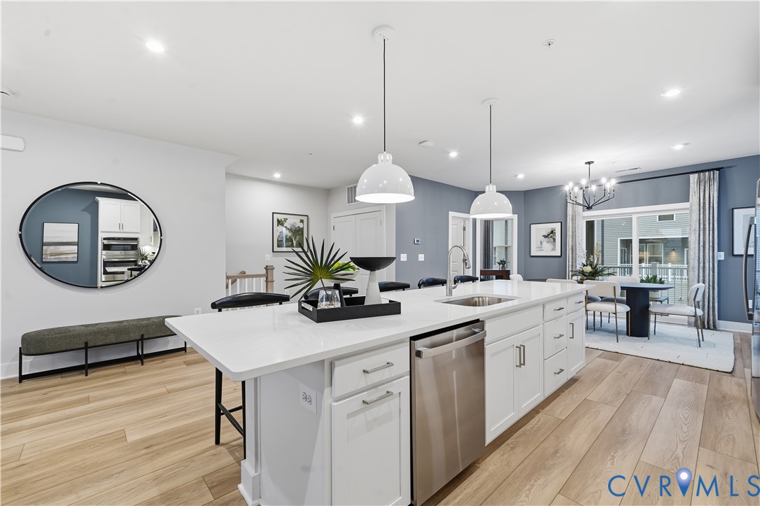 9881 Tuco Street, Unit B Glen Allen, VA 23059 - Photo 16 of 50 a kitchen with stainless steel appliances a kitchen island a stove a table a sink and a dining table with wooden floor