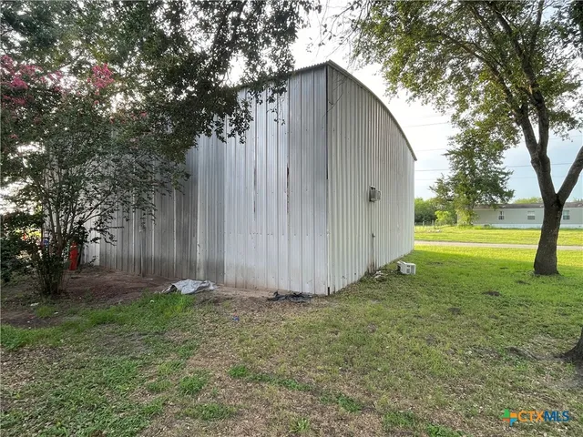 a view of backyard with large trees and wooden fence
