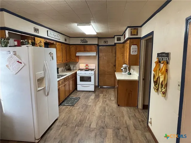 a kitchen with stainless steel appliances a refrigerator a sink and wooden floor