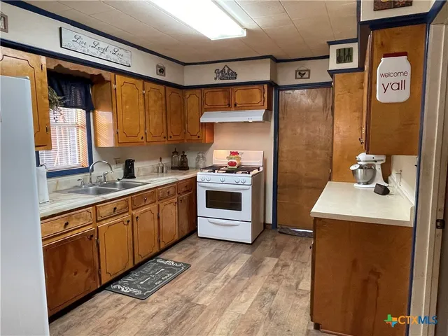 a kitchen with granite countertop a sink stove and refrigerator