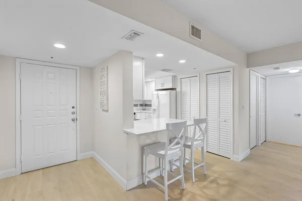 a view of kitchen with refrigerator and white cabinets