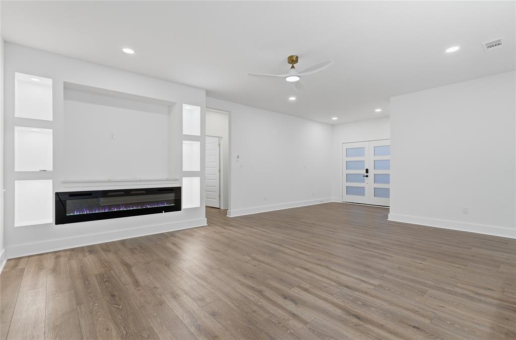 130 Cedar Elm Road Trinidad, TX 75163 - Photo 8 of 27 Spacious open-concept room featuring wood-finish flooring, a built-in media center with shelving and an electric fireplace, a modern ceiling fan, recessed lighting, and a double entry door with frosted glass panels