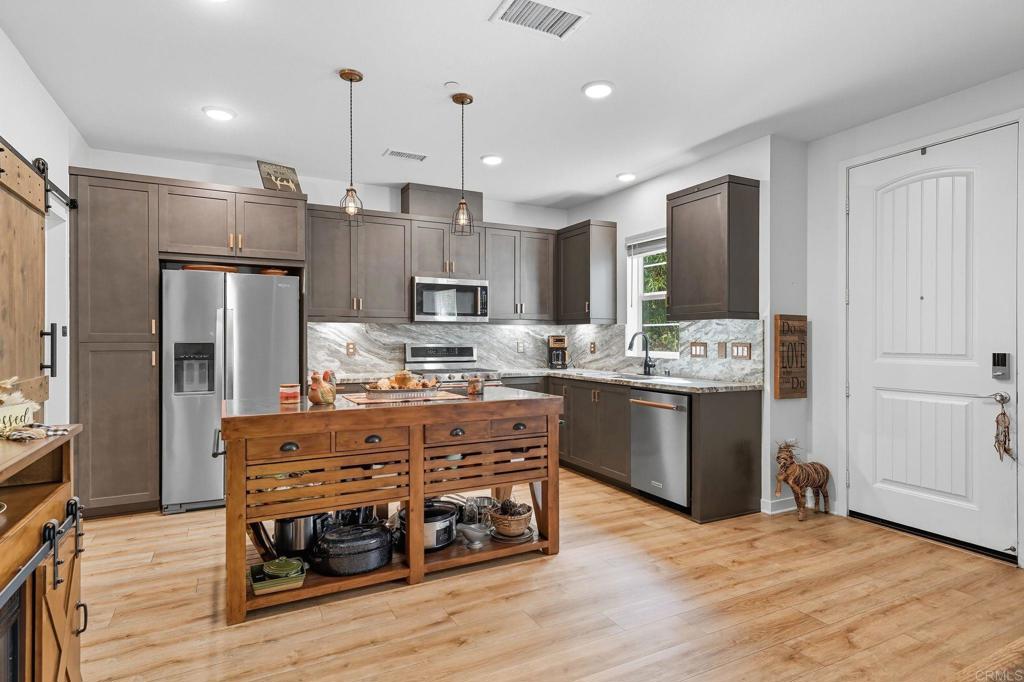 122 Diamante Road San Marcos, CA 92078 - Photo 2 of 36 a kitchen with kitchen island stainless steel appliances a stove refrigerator and cabinets