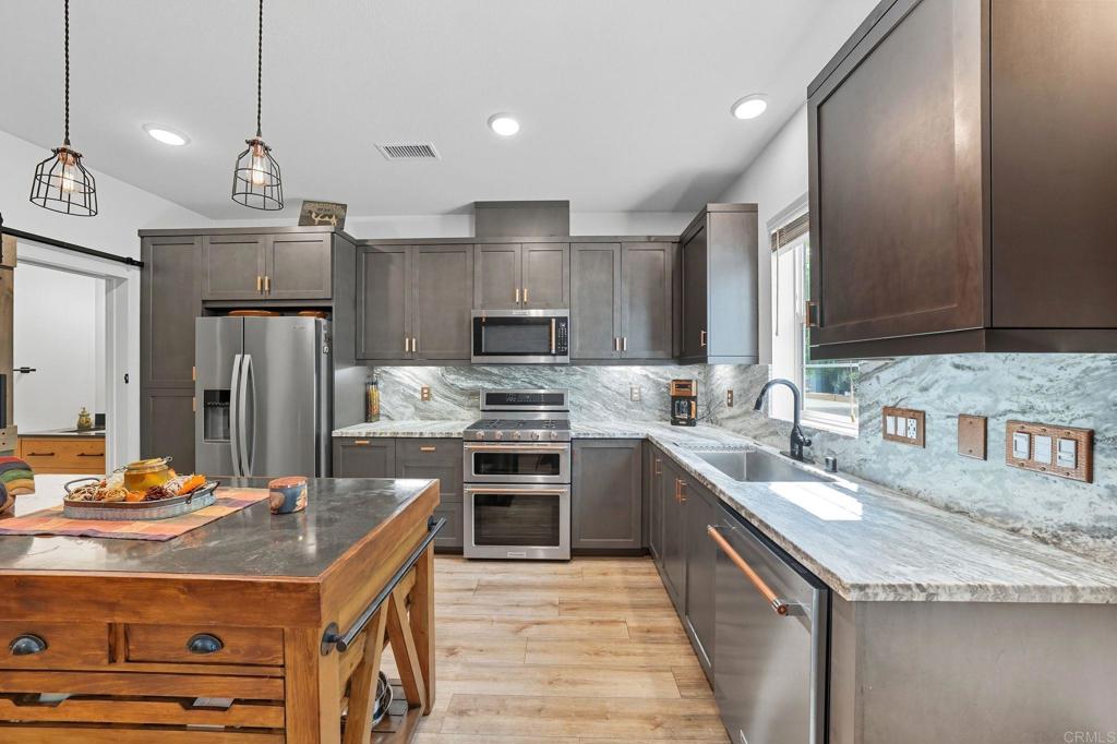 122 Diamante Road San Marcos, CA 92078 - Photo 3 of 36 a kitchen with kitchen island granite countertop a sink stainless steel appliances and cabinets