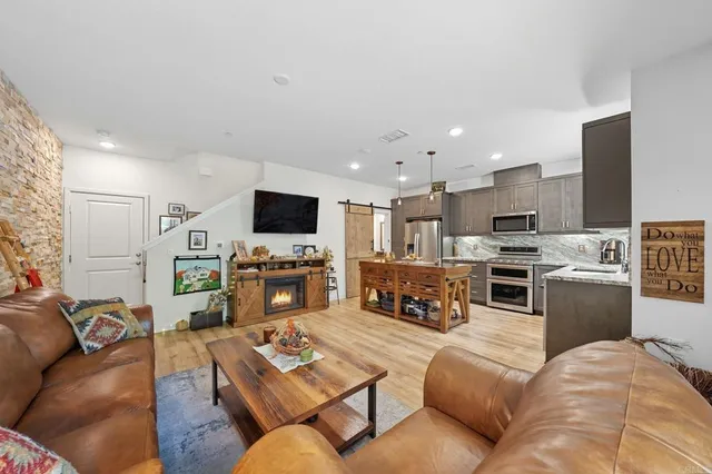 a living room with furniture and a flat screen tv with kitchen view