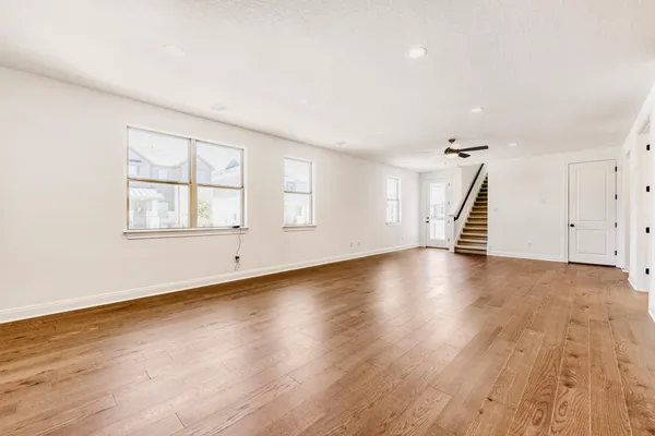 a view of empty room with wooden floor and ceiling fan