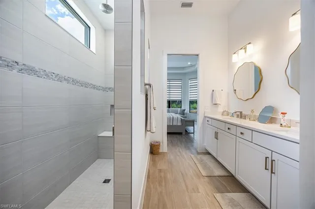 a spacious bathroom with a double vanity sink a mirror and a shower