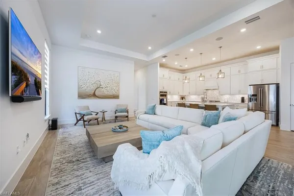 a living room with furniture kitchen view and a flat screen tv