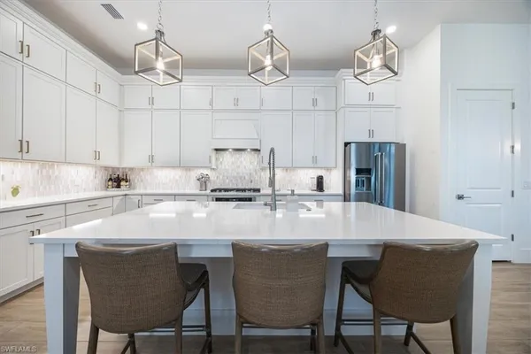 a kitchen with stainless steel appliances granite countertop a sink a stove and chairs