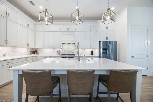 a kitchen with stainless steel appliances granite countertop a sink a stove and chairs