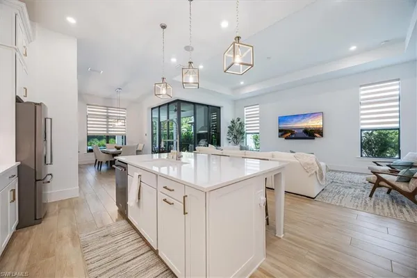 a large white kitchen with lots of counter space dining table and stainless steel appliances