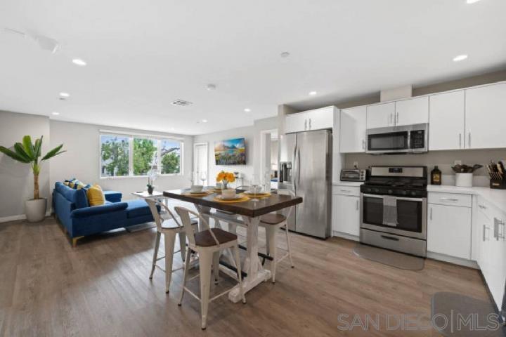 a kitchen with kitchen island granite countertop wooden floor stainless steel appliances and dining table