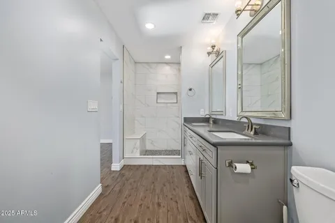 a bathroom with a granite countertop sink a toilet a mirror and shower