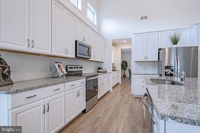 a kitchen with kitchen island granite countertop lots of counter top space and wooden floors