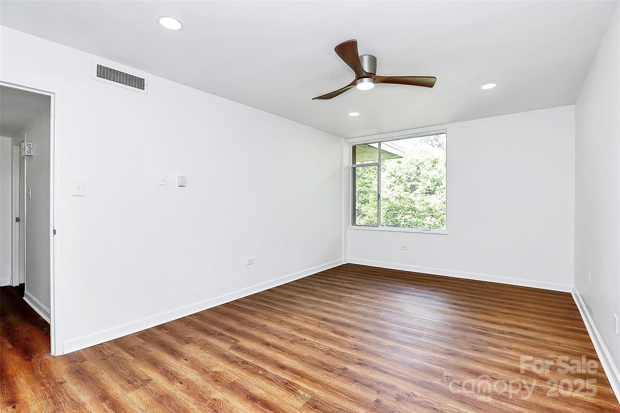 1300 Queens Road, Unit 405 Charlotte, NC 28207 - Photo 20 of 36 an empty room with wooden floor ceiling fan and windows