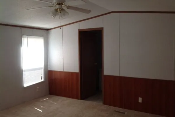 an empty room with windows and fan