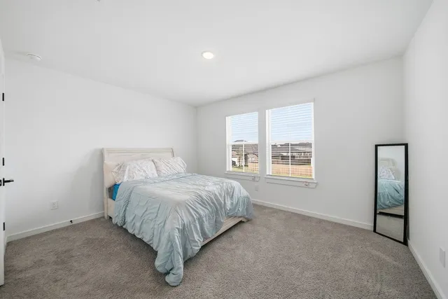 a bed sitting in a spacious bedroom next to a window