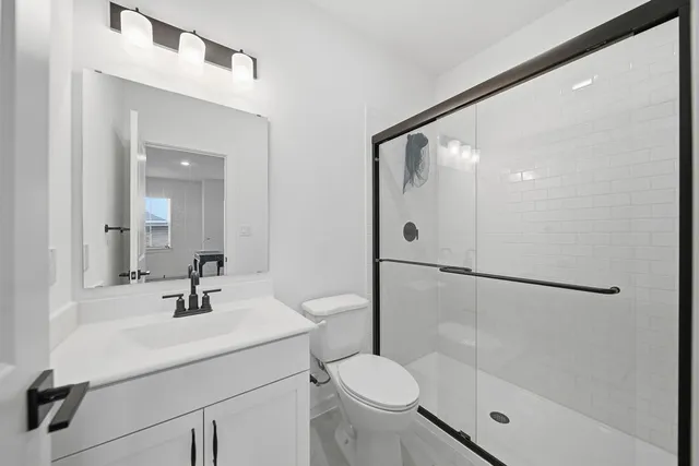 a bathroom with a shower sink mirror and a toilet