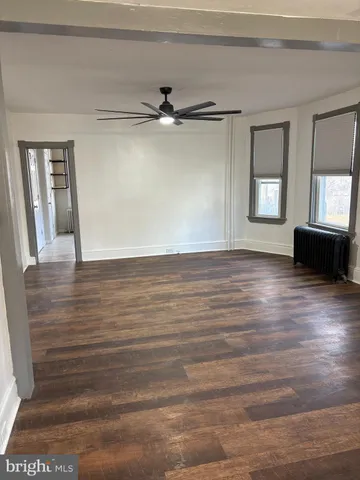 a view of an empty room with window and wooden floor