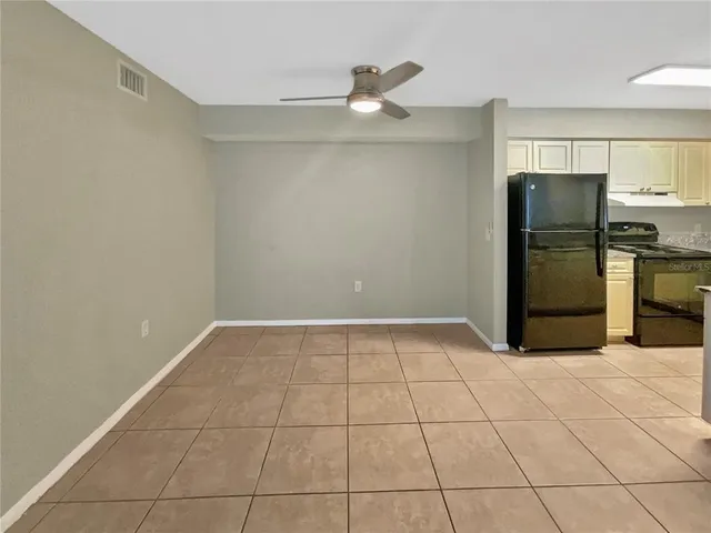 a view of a refrigerator in kitchen and an empty room