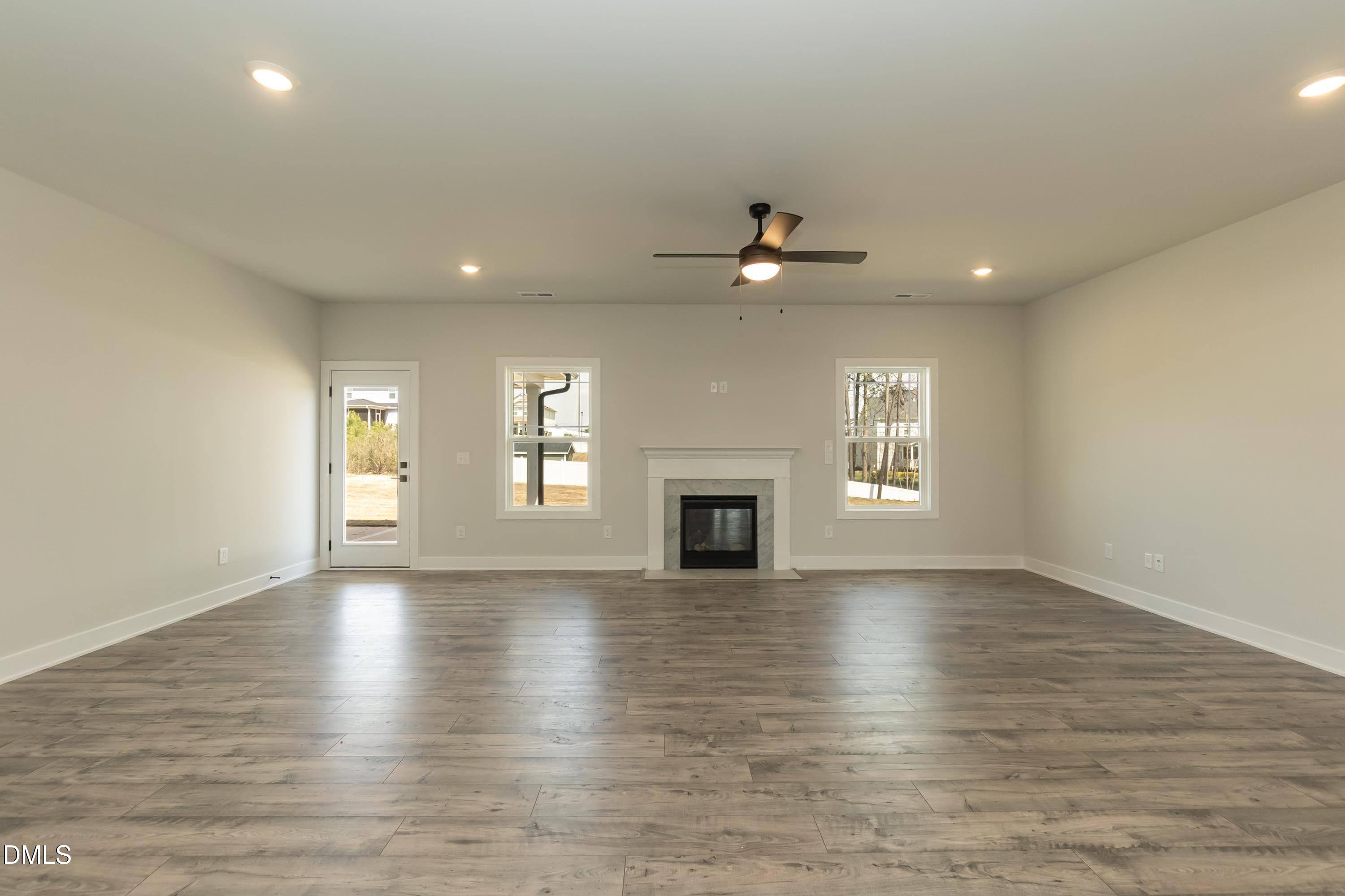 104 Galway Road Lillington, NC 27546 - Photo 18 of 40 an empty room with wooden floor fireplace and windows