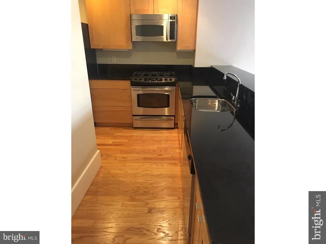 1615 Walnut Street, Unit 4 Philadelphia, PA 19102 - Photo 4 of 22 a kitchen with granite countertop cabinets and black stainless steel appliances