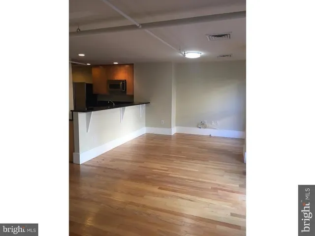 a view of a hallway with wooden floor and a bathroom