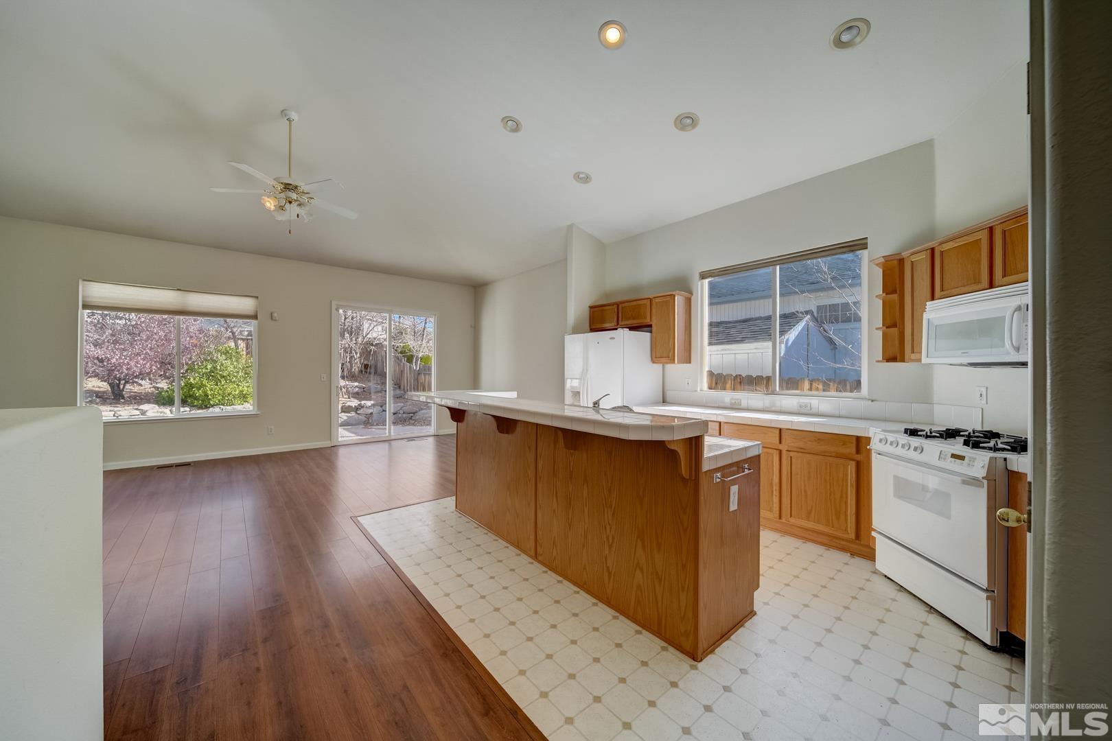 7560 Michaela Drive Reno, NV 89511 - Photo 4 of 32 a kitchen with stainless steel appliances granite countertop a stove a sink dishwasher and a refrigerator with wooden floor