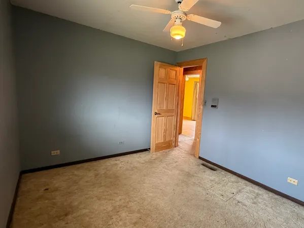 an empty room with a window and chandelier fan