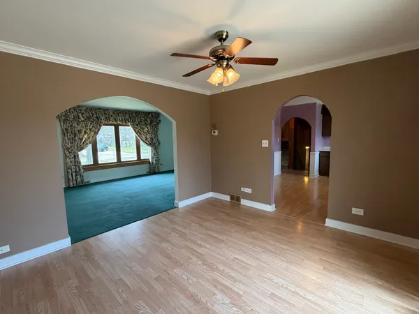 a view of a big room with a chandelier fan and a wooden floor