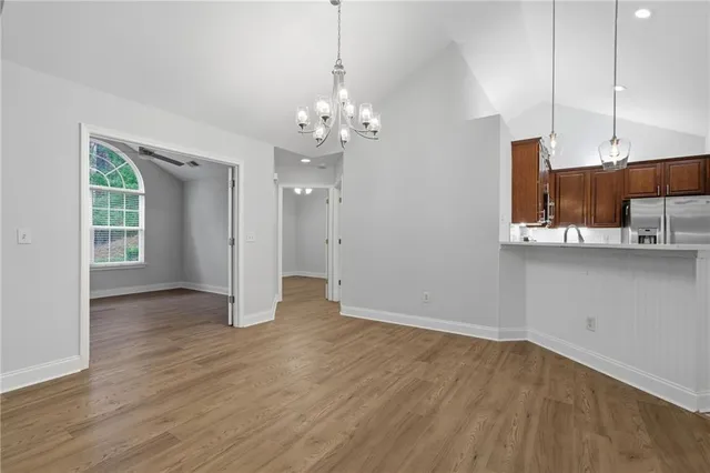 a view of an empty room with kitchen and window