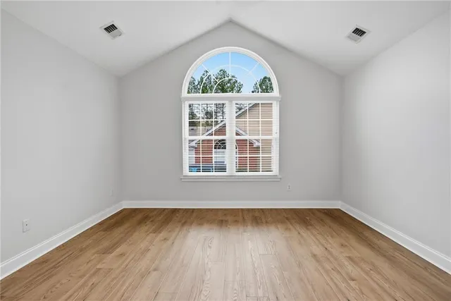 an empty room with wooden floor and windows