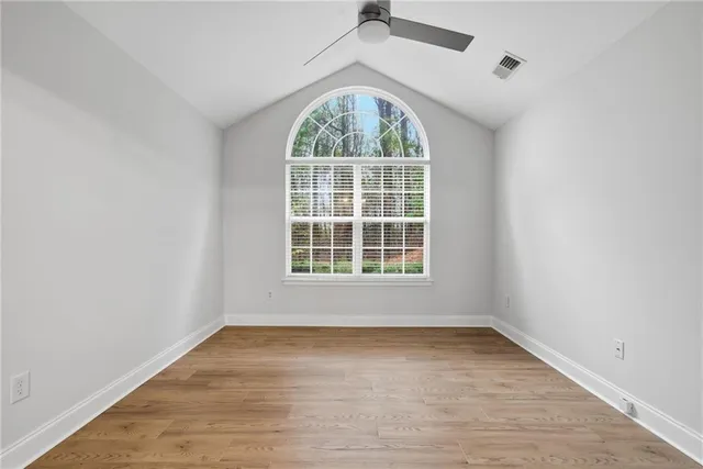 an empty room with wooden floor exposed radiator and windows