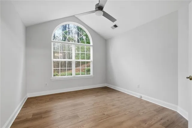 an empty room with wooden floor and windows