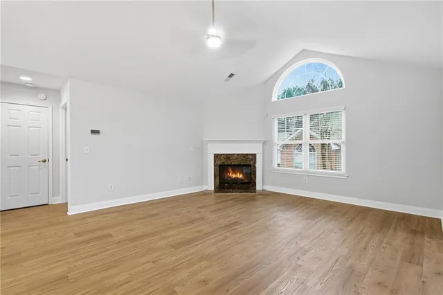 an empty room with windows fireplace and wooden floor