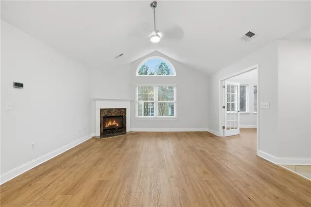 a view of an empty room with wooden floor fireplace and a window