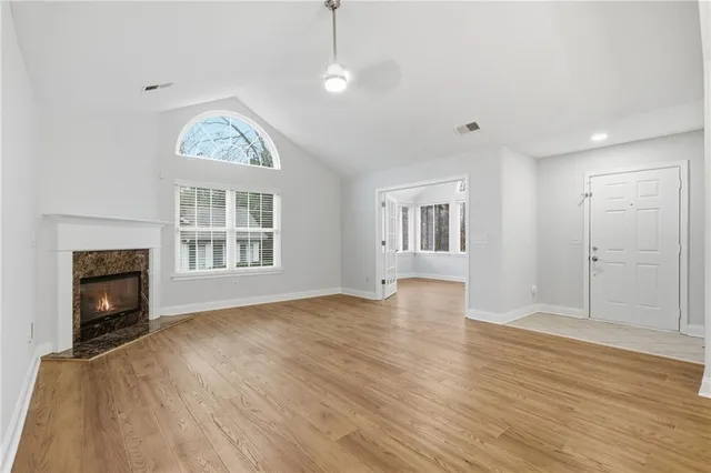 an empty room with wooden floor fireplace and windows