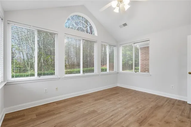 a view of an empty room with a window and wooden floor