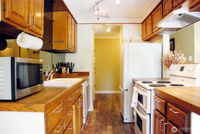 a kitchen with stainless steel appliances granite countertop a stove a sink dishwasher and a refrigerator with wooden floor