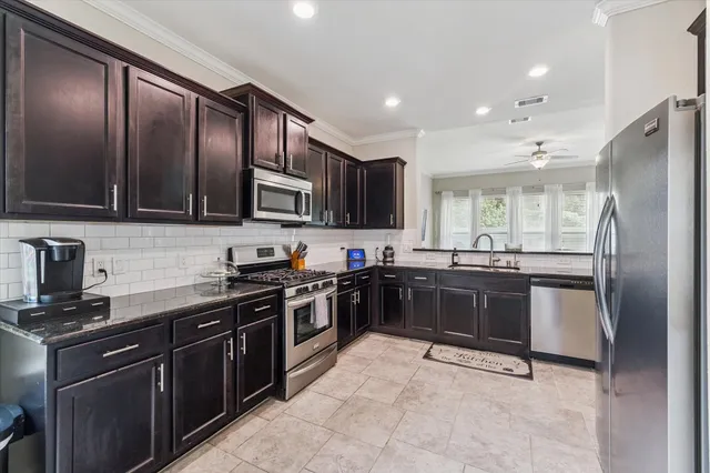 a kitchen with stainless steel appliances granite countertop wooden cabinets a stove a sink and a microwave
