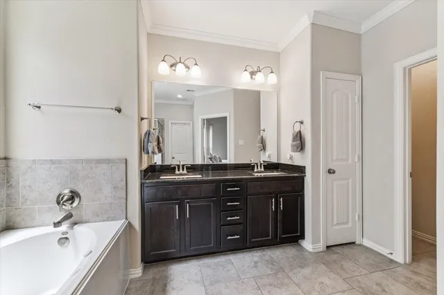 a spacious bathroom with a granite countertop double vanity sink a mirror and a bathtub