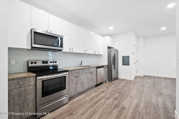 a kitchen with stainless steel appliances a stove a microwave and white cabinets