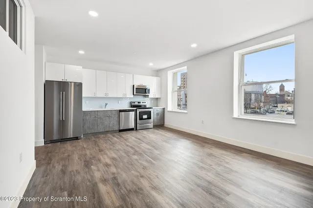 a large kitchen with stainless steel appliances granite countertop a refrigerator and a stove top oven