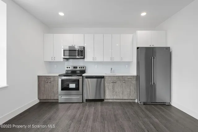 a kitchen with granite countertop white cabinets and stainless steel appliances