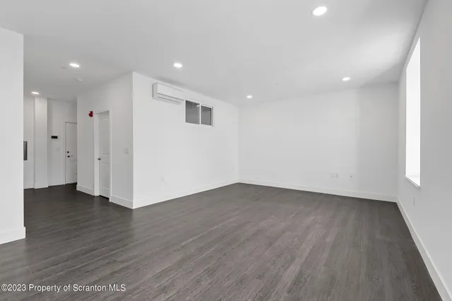 a view of an empty room with wooden floor and entryway