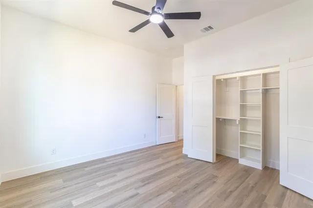 a view of a room with wooden floor and ceiling fan