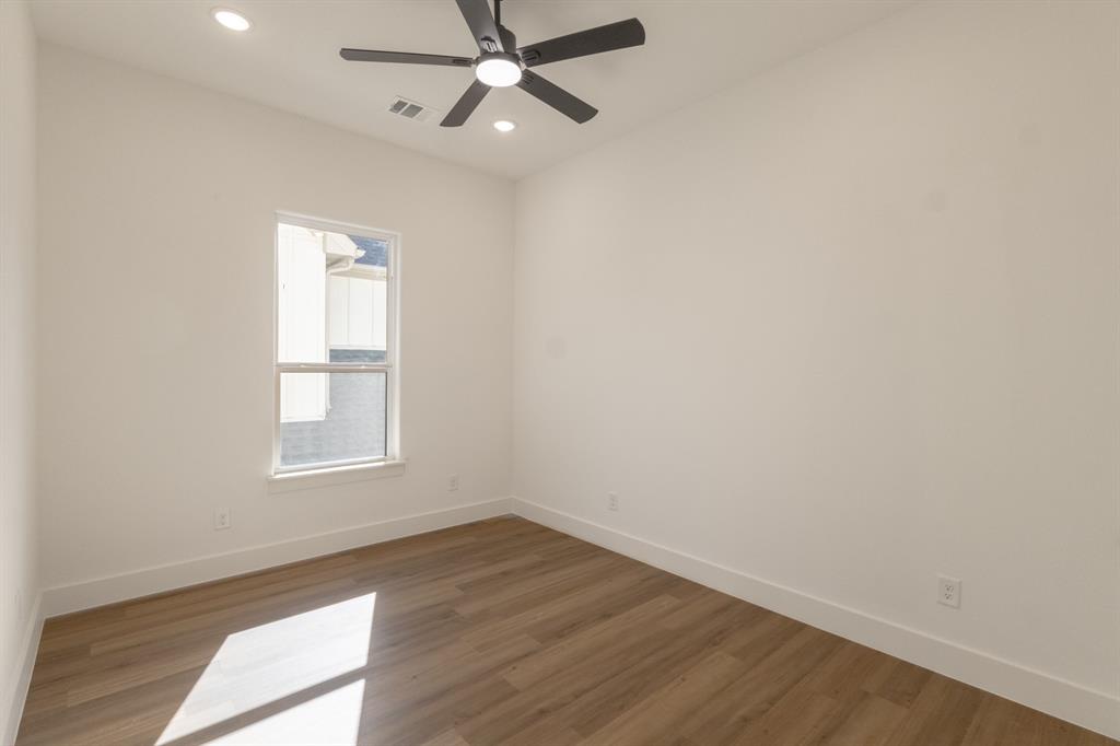 2900 8th Avenue Fort Worth, TX 76110 - Photo 17 of 32 an empty room with wooden floor fan and windows