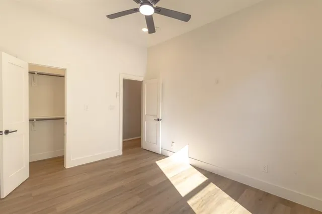 an empty room with wooden floor closet and windows