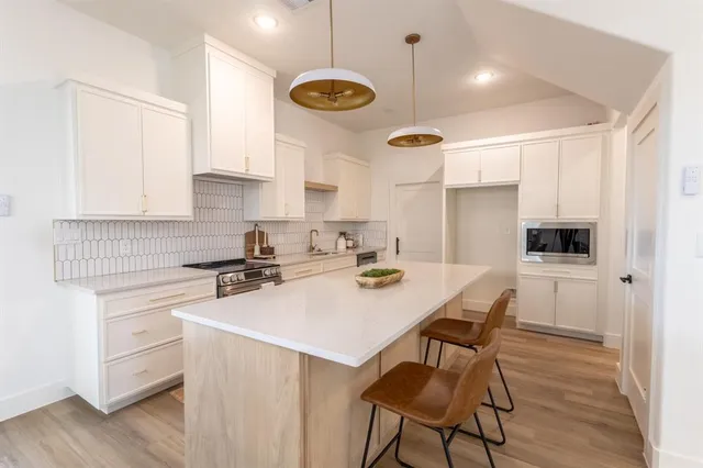 a kitchen with a sink a stove a refrigerator and white cabinets with wooden floor