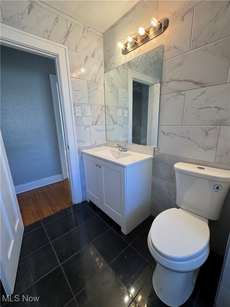 2121 Alton Road Cleveland, OH 44112 - Photo 32 of 44 Half bath featuring tile walls, vanity, dark tile patterned flooring, and a textured ceiling